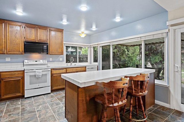 8468 Calle Morelos, San Diego, CA 92126 - kitchen with white appliances, tile counters, brown cabinets, and a breakfast bar