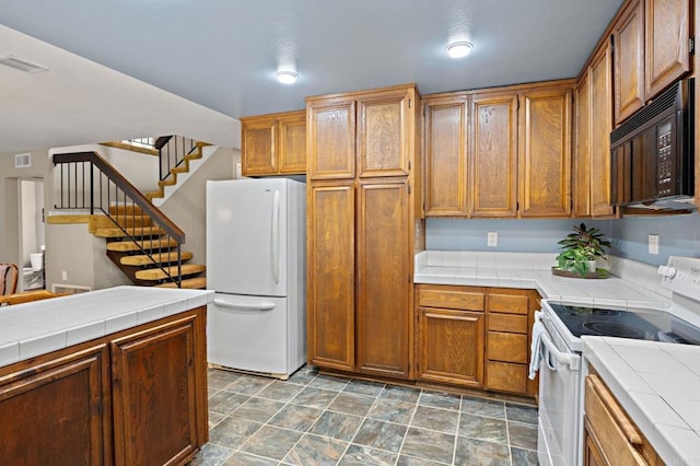 8468 Calle Morelos, San Diego, CA 92126 - kitchen featuring white appliances, tile countertops, brown cabinetry, and stone finish floors