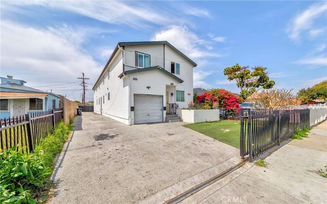 8711 Mckinley Pl, Los Angeles, CA 90002 - view of front of home with concrete driveway, a fenced front yard, a garage, and stucco siding