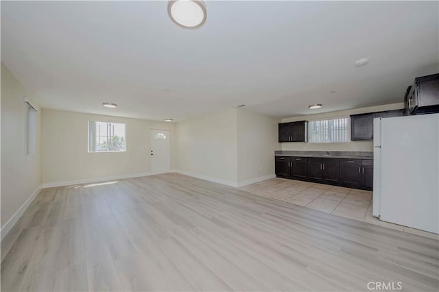 8711 Mckinley Pl, Los Angeles, CA 90002 - unfurnished living room with healthy amount of natural light, baseboards, and light wood-type flooring
