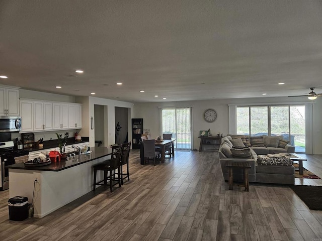 34885 Heartland Ln, Murrieta, CA 92563 - kitchen featuring stainless steel appliances, open floor plan, dark countertops, dark wood-type flooring, and recessed lighting