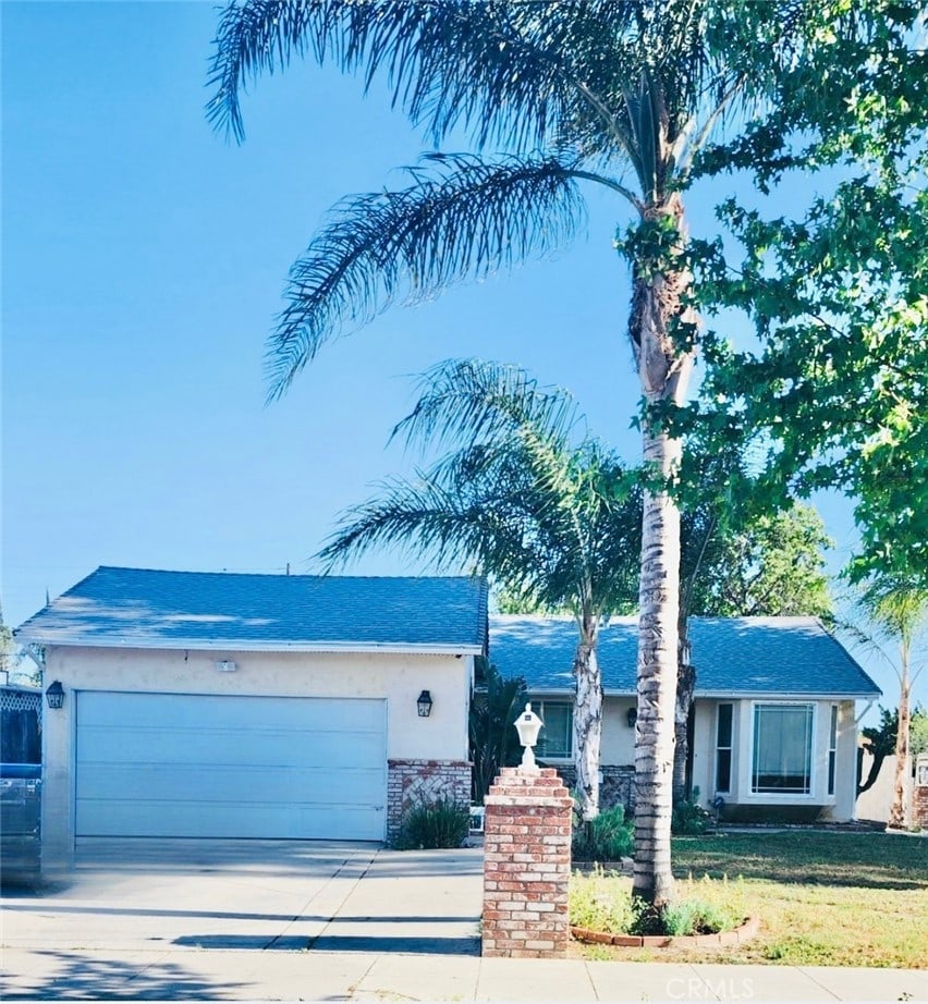 20554 Valerio St, Winnetka, CA 91306 - ranch-style house featuring an attached garage, concrete driveway, brick siding, a front lawn, and stucco siding