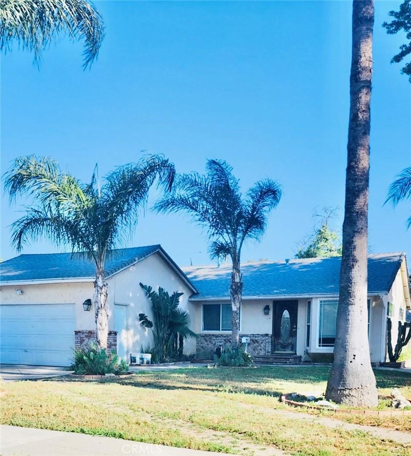 20554 Valerio St, Winnetka, CA 91306 - ranch-style house with stucco siding, an attached garage, a front yard, and stone siding