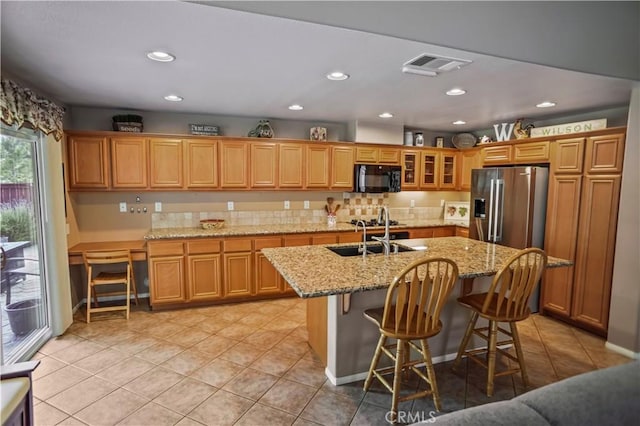 17334 Sierra Sunrise Ln, Canyon Country, CA 91387 - kitchen with black microwave, stainless steel refrigerator with ice dispenser, a sink, light tile patterned floors, and an island with sink