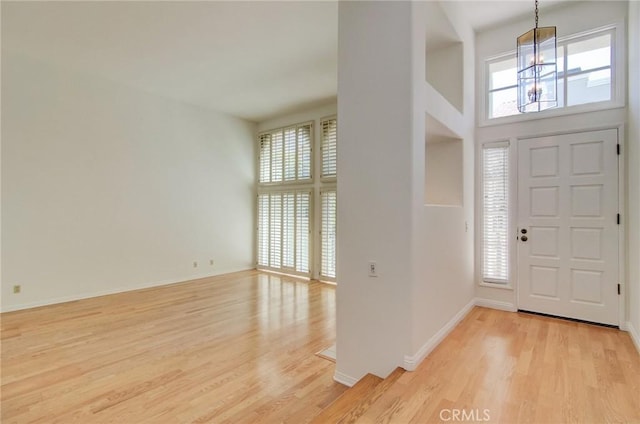 6052 Shadowbrook Cir, Huntington Beach, CA 92648 - entryway featuring a chandelier, light wood-type flooring, a towering ceiling, and baseboards