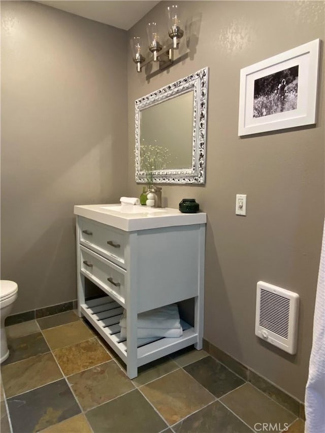 53434 Redwood Dr Unit B, Springville, CA 93265 - bathroom with toilet, vanity, baseboards, heating unit, and stone finish floors