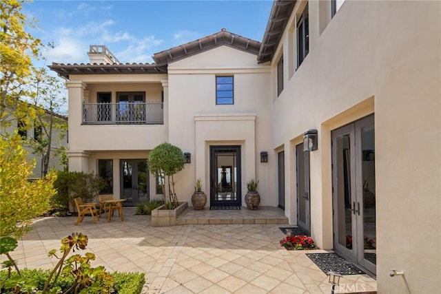 12 Via Avoria, Newport Coast, CA 92657 - property entrance featuring french doors, a patio, a chimney, stucco siding, and a balcony