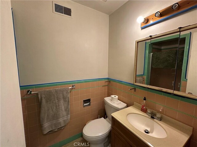 159 S Shasta St S, Willows, CA 95988 - bathroom featuring toilet, vanity, a wainscoted wall, tile walls, and an enclosed shower