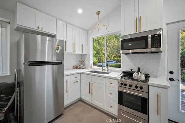 20955 De Mina St, Woodland Hills, CA 91364 - kitchen featuring appliances with stainless steel finishes, a sink, white cabinetry, backsplash, and vaulted ceiling