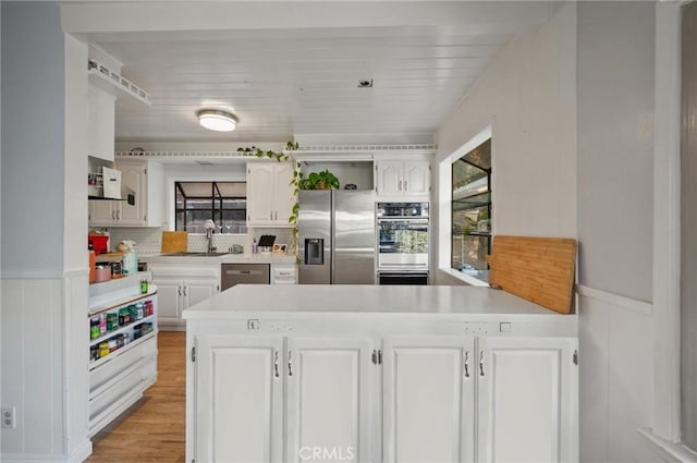 20955 De Mina St, Woodland Hills, CA 91364 - kitchen featuring appliances with stainless steel finishes, a peninsula, a sink, white cabinetry, and light countertops