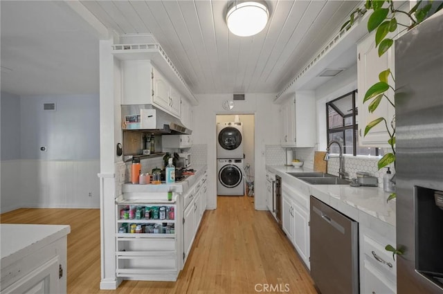 20955 De Mina St, Woodland Hills, CA 91364 - kitchen with appliances with stainless steel finishes, stacked washer and clothes dryer, a sink, light countertops, and white cabinetry