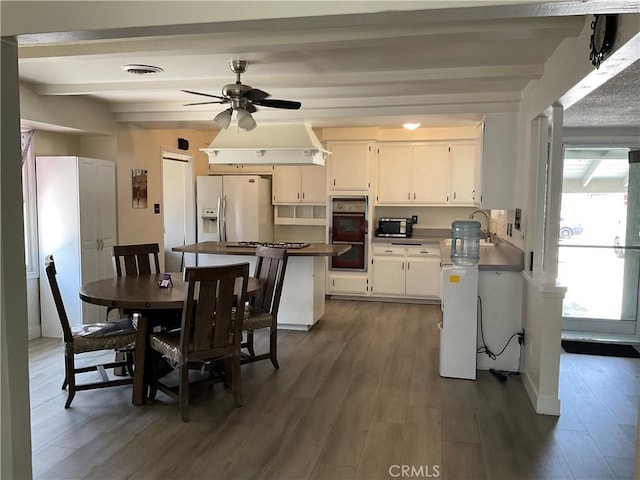 2113 N Lewis St, Santa Ana, CA 92706 - kitchen featuring white fridge with ice dispenser, double oven, beam ceiling, wood finished floors, and white cabinets
