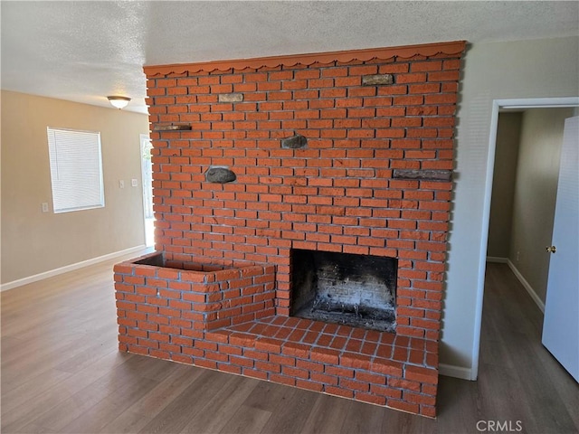 6025 Florence St, Riverside, CA 92504 - detailed view of wood finished floors, a brick fireplace, a textured ceiling, and baseboards