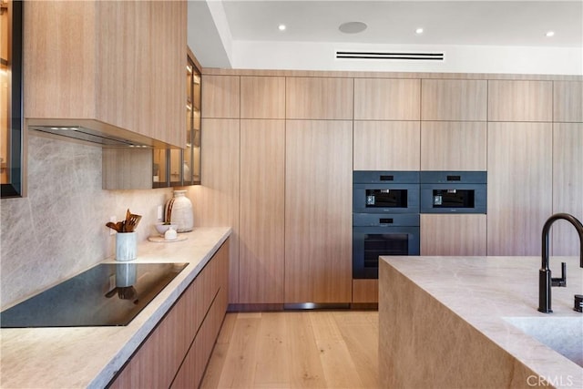 4314 Teesdale Ave, Studio City, CA 91604 - kitchen featuring black electric cooktop, modern cabinets, double oven, light wood finished floors, and a sink