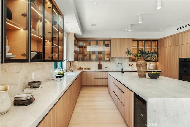 4314 Teesdale Ave, Studio City, CA 91604 - kitchen featuring modern cabinets, wine cooler, light wood-style floors, decorative backsplash, and a sink