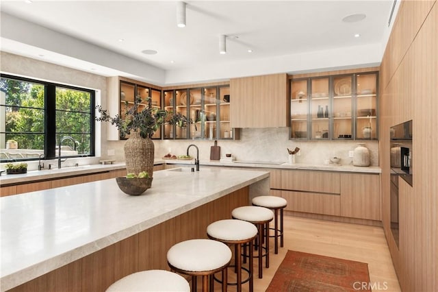 4314 Teesdale Ave, Studio City, CA 91604 - kitchen featuring modern cabinets, a kitchen bar, glass insert cabinets, tasteful backsplash, and recessed lighting