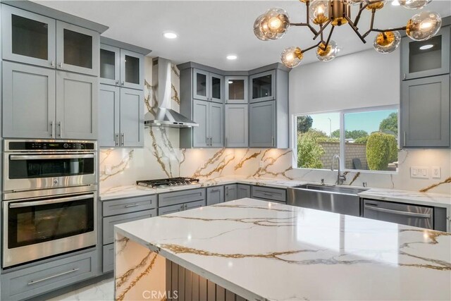 9455 Brandon Ct, Northridge, CA 91325 - kitchen with wall chimney range hood, appliances with stainless steel finishes, gray cabinets, light stone counters, and recessed lighting