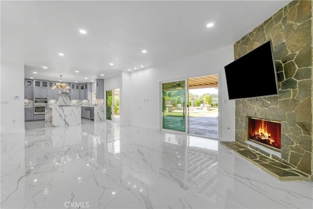 9455 Brandon Ct, Northridge, CA 91325 - unfurnished living room with a stone fireplace, recessed lighting, plenty of natural light, light marble finish floors, and a chandelier