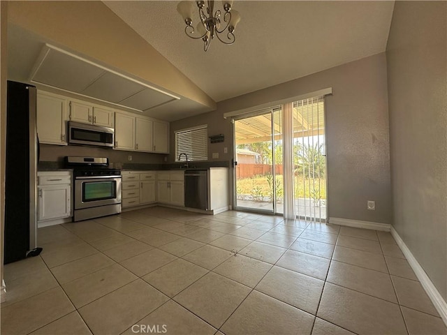 16193 Space Dr, Moreno Valley, CA 92551 - kitchen featuring appliances with stainless steel finishes, baseboards, white cabinetry, light tile patterned floors, and lofted ceiling