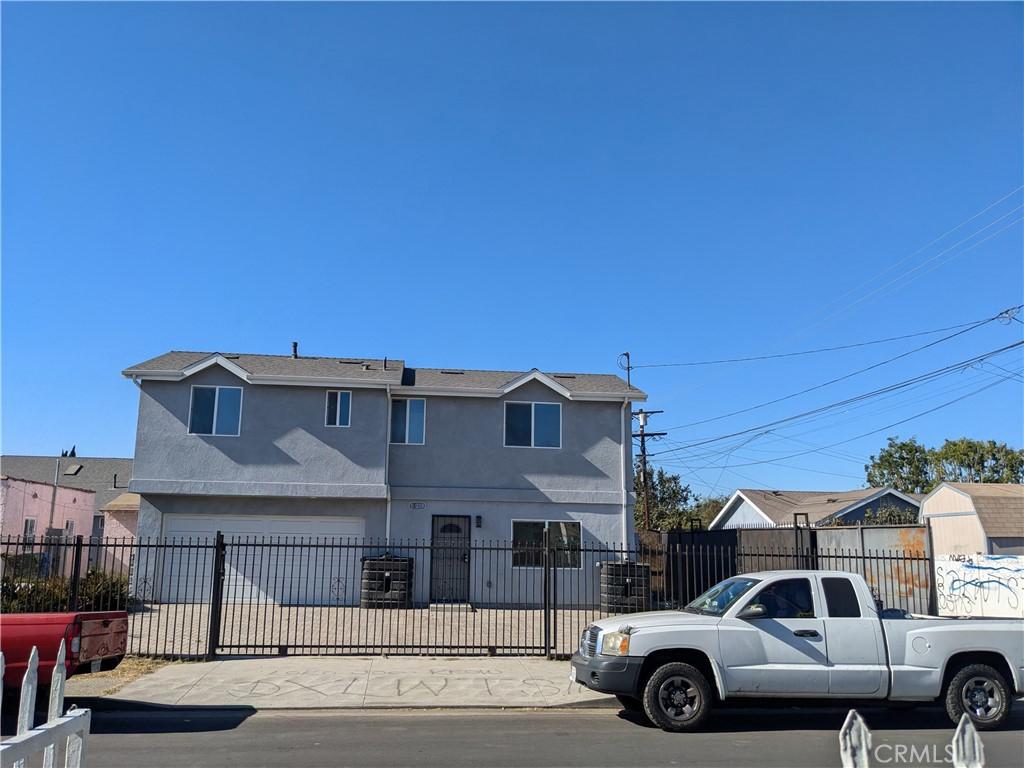 1977 E 113th St, Los Angeles, CA 90059 - view of front of home with stucco siding, a fenced front yard, a garage, and concrete driveway