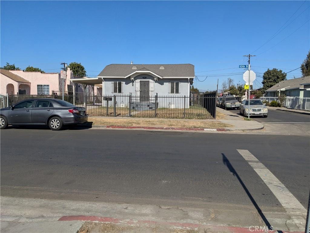 1977 E 113th St, Los Angeles, CA 90059 - view of front facade with stucco siding and a fenced front yard