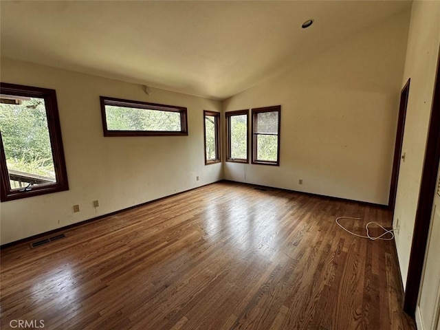 50771 Woodside Ln, Oakhurst, CA 93644 - empty room with healthy amount of natural light, wood finished floors, lofted ceiling, and baseboards