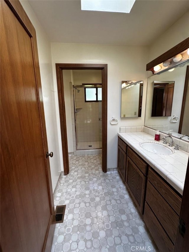 50771 Woodside Ln, Oakhurst, CA 93644 - full bathroom with a stall shower, vanity, a skylight, and tile patterned floors