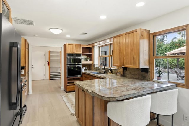 233233A Cole Ranch Rd, Encinitas, CA 92024 - kitchen with freestanding refrigerator, a peninsula, double oven, a sink, and light wood-style flooring