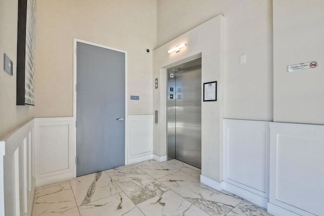 800 Grand Ave Unit 205, Carlsbad, CA 92008 - corridor featuring elevator, light marble finish flooring, wainscoting, and a decorative wall