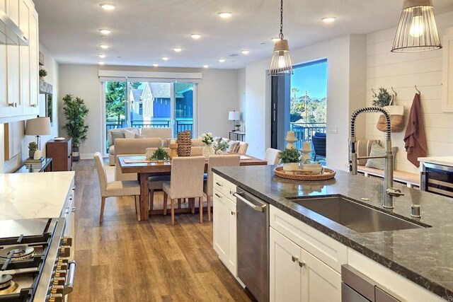 800 Grand Ave Unit 205, Carlsbad, CA 92008 - kitchen featuring a sink, wood finished floors, open floor plan, stainless steel appliances, and white cabinetry