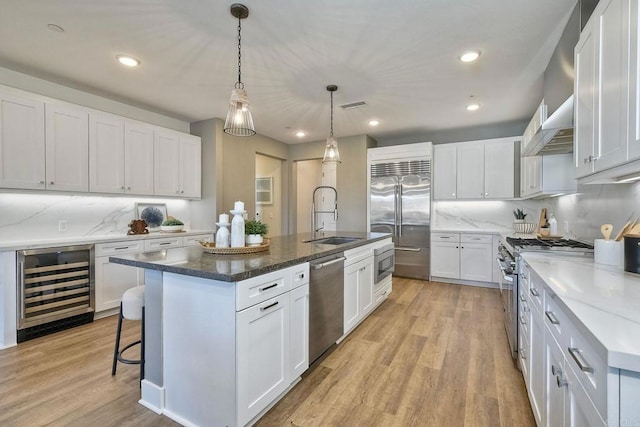 800 Grand Ave Unit 205, Carlsbad, CA 92008 - kitchen featuring built in appliances, a sink, beverage cooler, a center island with sink, and light wood-style flooring