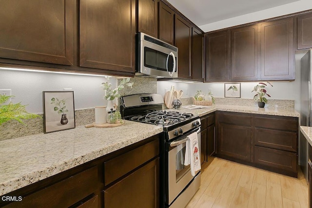 953 Coronado Cir, Santa Paula, CA 93060 - kitchen featuring appliances with stainless steel finishes, dark brown cabinets, light wood finished floors, and light stone countertops