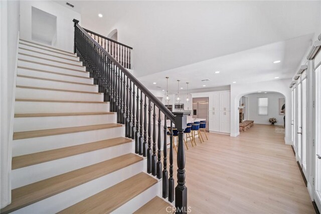 25422 Magnolia Ln, Stevenson Ranch, CA 91381 - stairs featuring arched walkways, wood finished floors, and recessed lighting