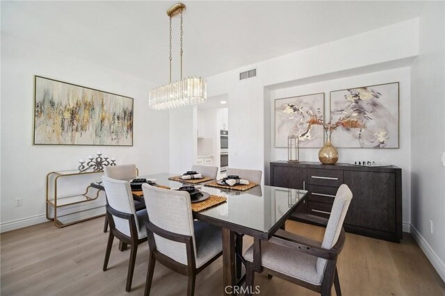 25422 Magnolia Ln, Stevenson Ranch, CA 91381 - dining space with light wood-style flooring, a chandelier, and baseboards