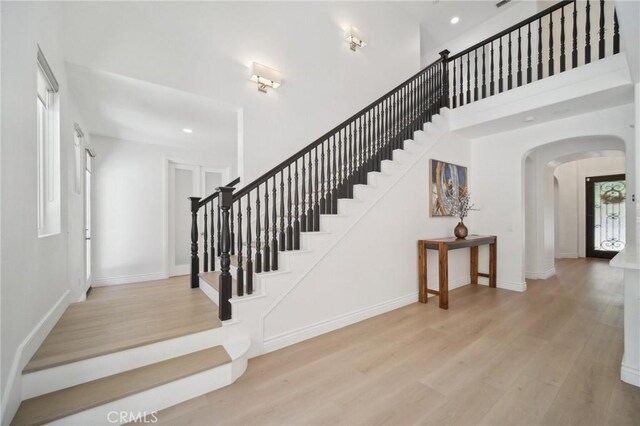 25422 Magnolia Ln, Stevenson Ranch, CA 91381 - stairs featuring wood finished floors, arched walkways, recessed lighting, baseboards, and a towering ceiling