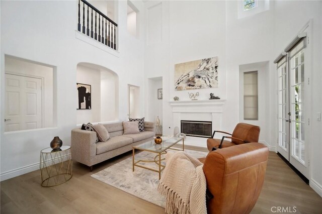 25422 Magnolia Ln, Stevenson Ranch, CA 91381 - living room with a towering ceiling, arched walkways, plenty of natural light, wood finished floors, and baseboards