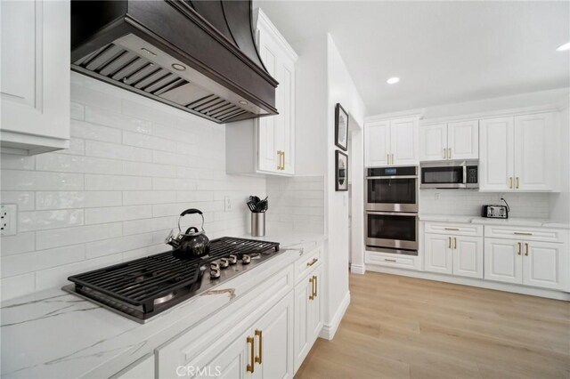 25422 Magnolia Ln, Stevenson Ranch, CA 91381 - kitchen with premium range hood, appliances with stainless steel finishes, decorative backsplash, white cabinetry, and light stone countertops