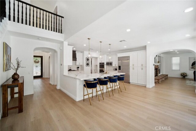 25422 Magnolia Ln, Stevenson Ranch, CA 91381 - kitchen featuring stainless steel appliances, arched walkways, a breakfast bar area, a peninsula, and light wood finished floors