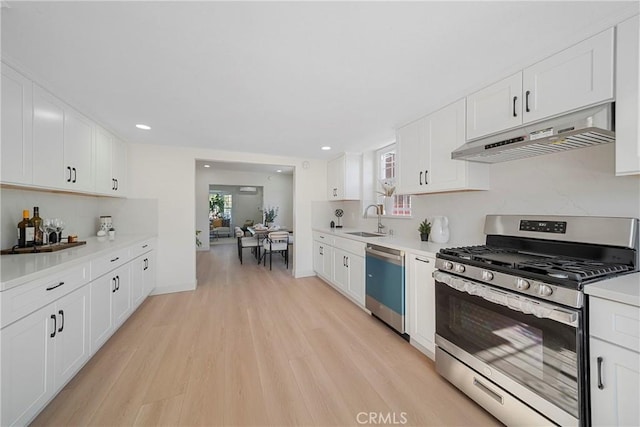 3825 Welland Ave, Los Angeles, CA 90008 - kitchen featuring stainless steel appliances, under cabinet range hood, a sink, light wood-style flooring, and white cabinets