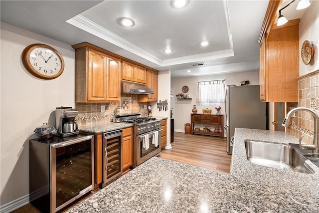 12713 16th St, Chino, CA 91710 - kitchen featuring under cabinet range hood, stainless steel appliances, a sink, a raised ceiling, and wine cooler