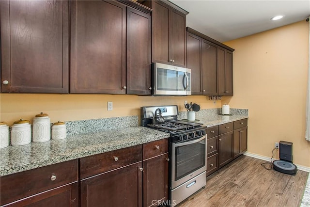 11294 Chappell Way, Beaumont, CA 92223 - kitchen featuring appliances with stainless steel finishes, light wood finished floors, dark brown cabinets, baseboards, and light stone countertops