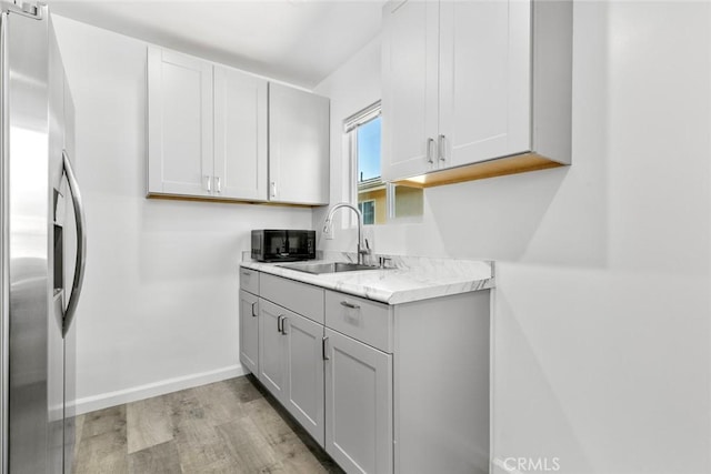 142 S Savannah St, Los Angeles, CA 90033 - kitchen with stainless steel fridge, light wood-style flooring, light countertops, a sink, and baseboards