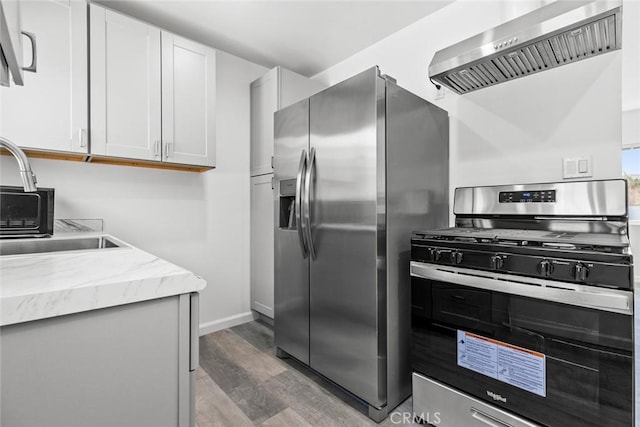 142 S Savannah St, Los Angeles, CA 90033 - kitchen featuring stainless steel appliances, exhaust hood, light wood-type flooring, a sink, and light stone countertops