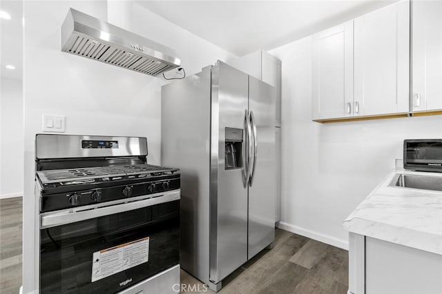 142 S Savannah St, Los Angeles, CA 90033 - kitchen with stainless steel appliances, wall chimney exhaust hood, dark wood finished floors, white cabinets, and baseboards