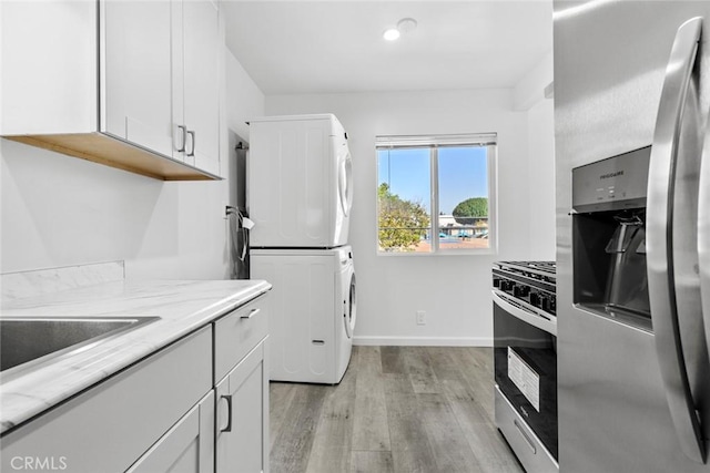 142 S Savannah St, Los Angeles, CA 90033 - kitchen featuring stacked washer and clothes dryer, stainless steel appliances, light wood finished floors, baseboards, and light stone counters