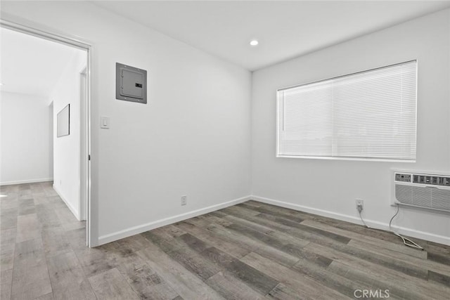 142 S Savannah St, Los Angeles, CA 90033 - spare room with electric panel, a wall mounted air conditioner, wood finished floors, recessed lighting, and baseboards