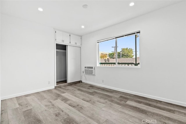 142 S Savannah St, Los Angeles, CA 90033 - unfurnished bedroom with a wall mounted AC, light wood-type flooring, recessed lighting, a closet, and baseboards
