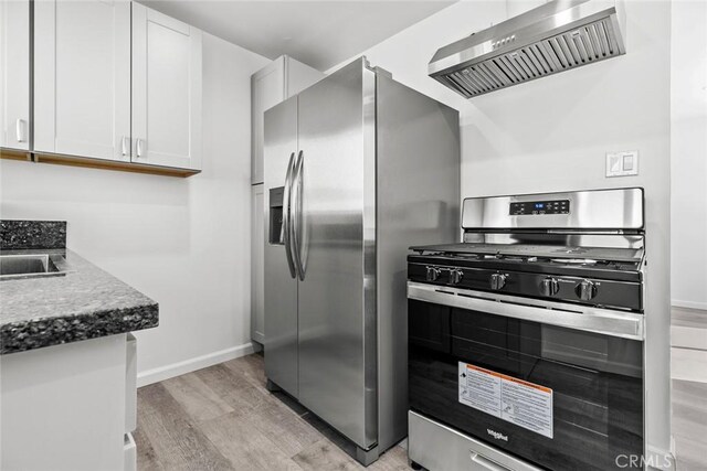 142 S Savannah St, Los Angeles, CA 90033 - kitchen featuring stainless steel appliances, wall chimney range hood, baseboards, light wood finished floors, and white cabinets