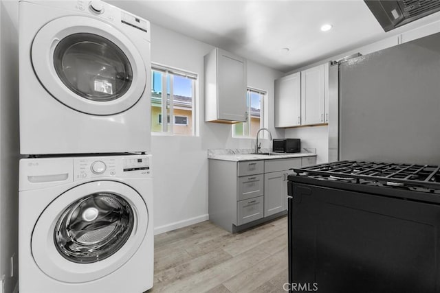 142 S Savannah St, Los Angeles, CA 90033 - laundry area featuring stacked washer and clothes dryer, light wood-style flooring, baseboards, and recessed lighting