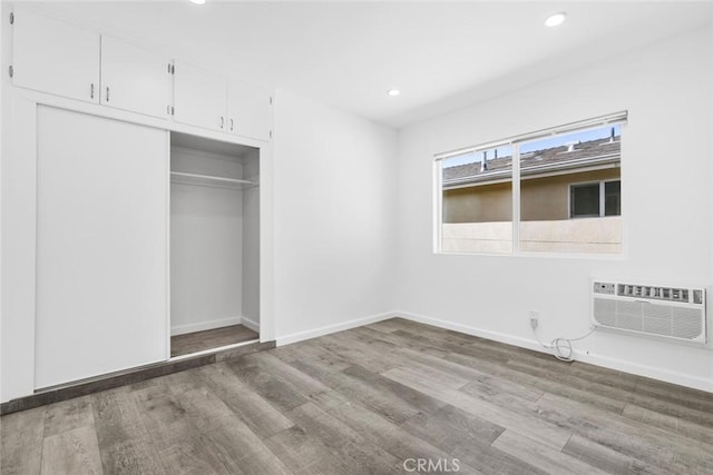 142 S Savannah St, Los Angeles, CA 90033 - unfurnished bedroom with a wall unit AC, wood finished floors, a closet, recessed lighting, and baseboards